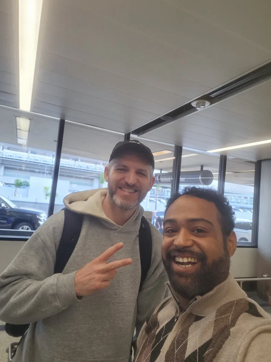 JC grinning in an airport selfie with another traveler during BET Awards Weekend