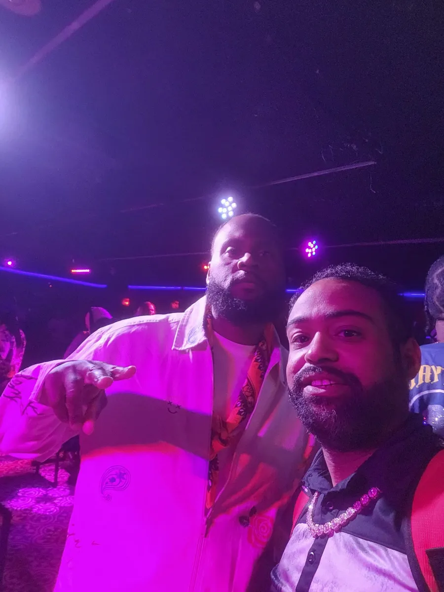 JC and another guest posing together under purple lights at a BET weekend event