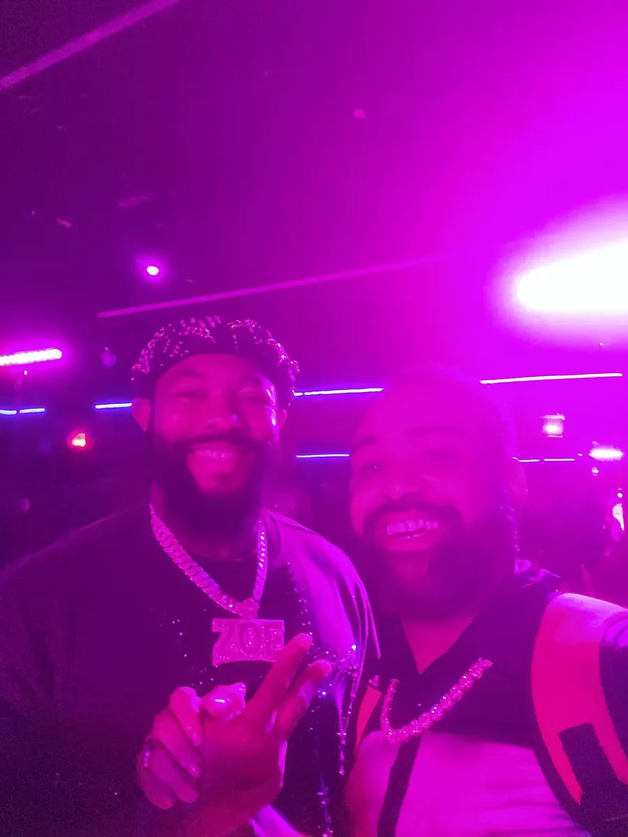 JC laughing in a selfie with another guest wearing a large pendant chain at a BET weekend event